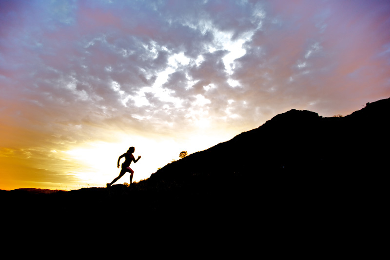 Paul Diffley Runner in silhouette against rising sun, running uphill
